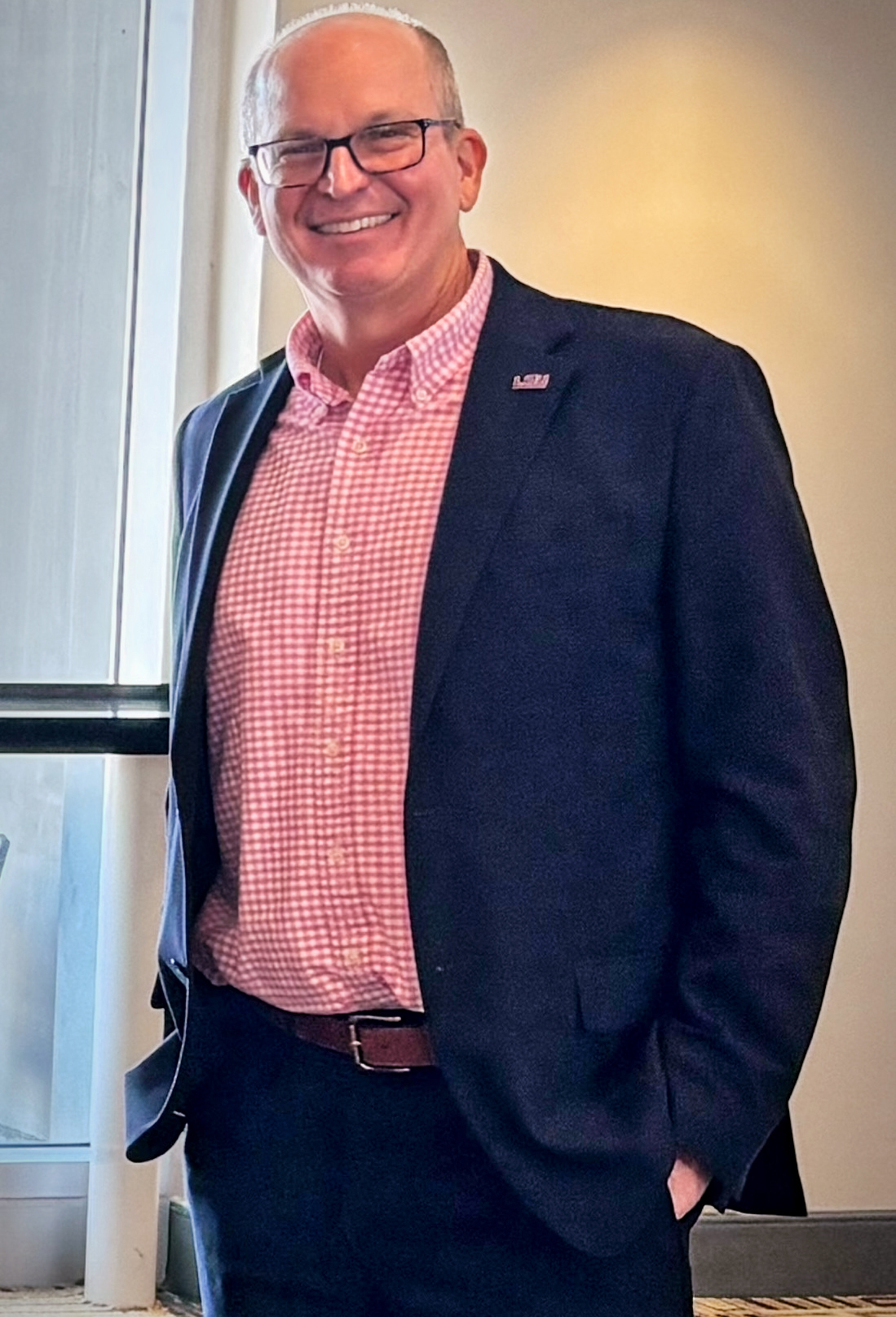 Dean Russell Crook wearing dark pants and a jacket and a checked shirt.